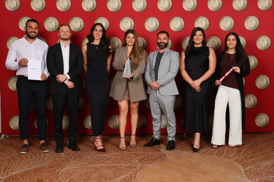 Members of the Jameson Law team at an awards presentation, holding an award.